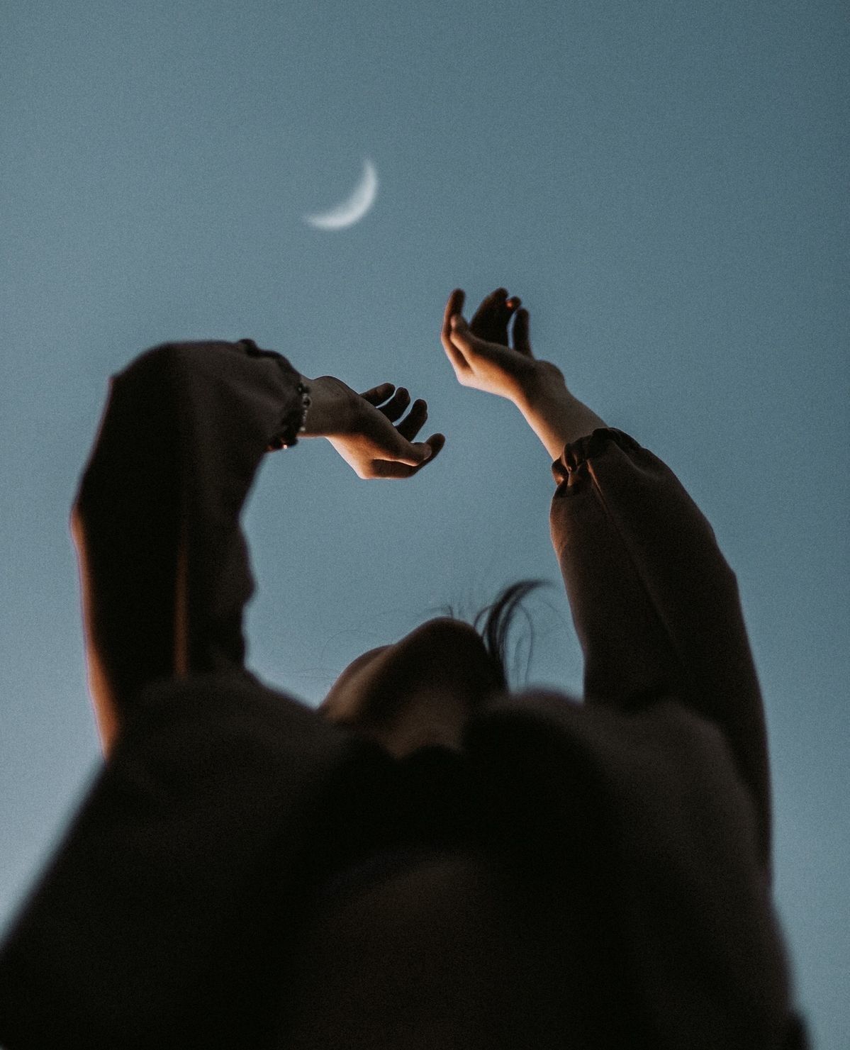 Hands reaching to the crescent moon.